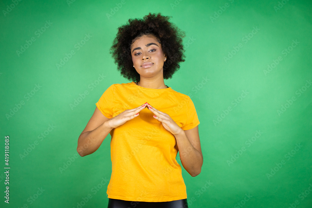 Wall mural african american woman wearing orange casual shirt over green background with hands together and fin