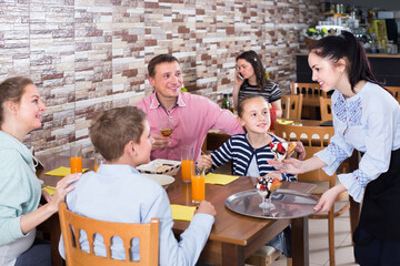 positive brunette waitress serving cheerful family in comfy family cafe