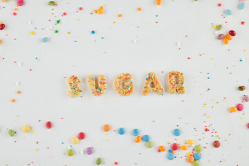 Word sugar made of cookie letters and rainbow sprinkles on white background, view from the top