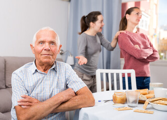 Family quarrel between the sisters. Elderly father sitting at the dinner table. 