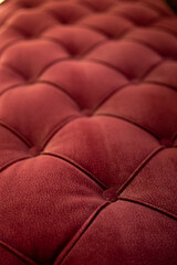 Close up textured red velvet fabric modern sofa with sunken buttons.