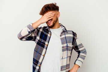 Young Moroccan man isolated on white background laughs joyfully keeping hands on head. Happiness concept.