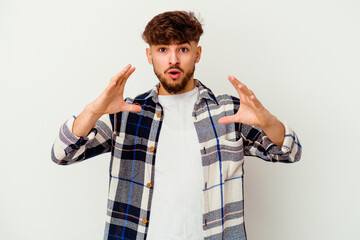 Young Moroccan man isolated on white background holding something with palms, offering to camera.