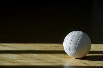 Volleyball ball on hardwood court floor with natural lighting. Team sport. Workout online concept