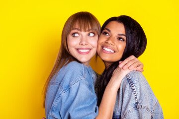 Profile photo of two pretty cheerful persons hugging look interested empty space isolated on yellow color background
