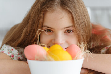 white cute European girl 10 years old with yellow and pink easter eggs close up