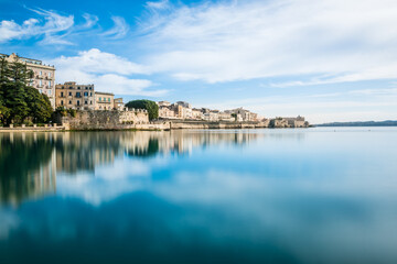 Ortigia, Syracuse, Italy / December 2018: Coast of Ortigia island at city of Syracuse. Long exposure sea. Reflection in water. Landscape reflection in sea