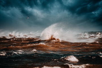 Storm clouds above the Baltic sea in winter. Dramatic sky, waves and water splashes. Dark seascape. Latvia.