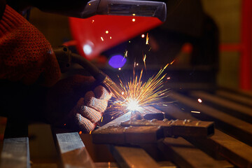A man in a protective mask carries out welding work in the garage.
