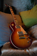 Les Paul Style E-Gitarre drapiert auf einer Sofa-Landschaft auf mehreren Kissen