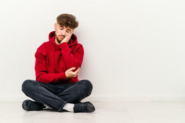 Young Moroccan man sitting on the floor isolated on white background who is bored, fatigued and need a relax day.