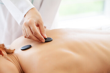 Young woman getting hot stone massage in spa salon.