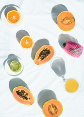 Summer fruits vibes. Summer, morning breakfast still life with fresh fruits: papaya, melon, citrus, avocado on a white background with bright sunlight, flat lay