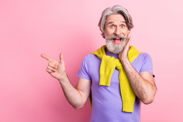 Portrait of attractive amazed cheery gray-haired man showing copy space offer new novelty isolated...