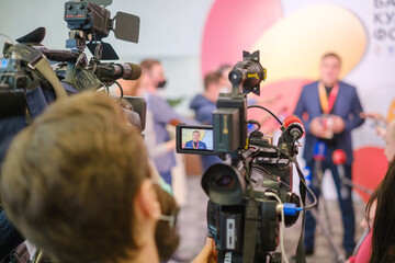 Cameras recording businessman delivering speech to journalists