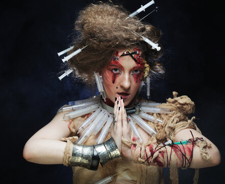 A young woman in a zombie costume - wrapped in bandages and with syringes in her hair. Creative image for the party. Halloween theme.