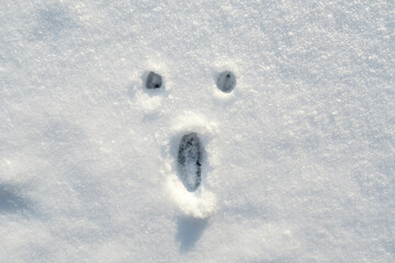 A surprised smiley face painted on the snow, on a sunny winter day. Copy space. 