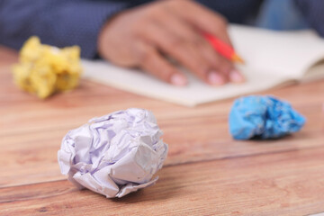 crumpled paper ball and man's hand on a notepad on background 