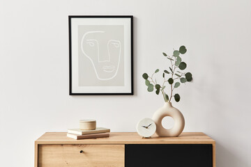 Stylish interior of living room with mock up poster frame, wooden commode, book, leaf in ceramic...