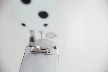 Close up picture of sewing-machine in white color. Macro sewing needle in fashion design atelier. Copy space for text and wallpaper pictures. Concept of factory, home, at work, professionals.
