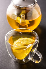 Ginger tea with lemon and honey in crystal glass on black background