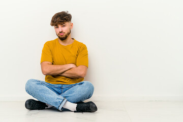 Fototapeta premium Young Moroccan man sitting on the floor isolated on white background who is bored, fatigued and need a relax day.