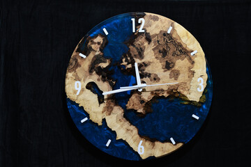Wall clock made of wood and blue epoxy resin isolated on black background. On the clock 23:45