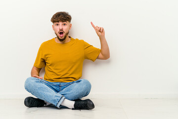 Young Moroccan man sitting on the floor isolated on white background having some great idea, concept of creativity.