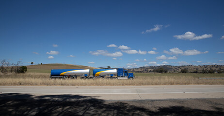 Truck on a freeway in an Australian Country Town midway between Sydney and Melbourne with nice blue sky and lush green trees as a backdrop