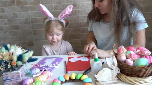 Mother and her baby have fun while painting easter eggs