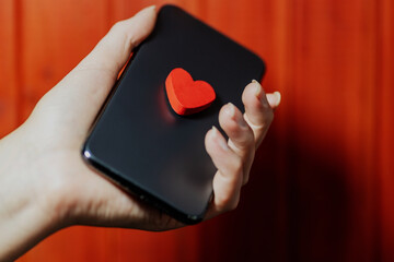 female hand holding a smartphone with a love heart. concept of long-distance relationship