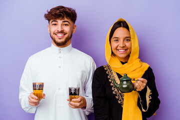 Young Moroccan couple drinking tea celebrating ramadan month isolated on purple background