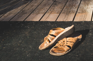 Pair of women's sandals on worn deck carpet.