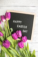 Happy Easter lettering on board surrounded purple flowers. Greeting card, ad, promotion, poster, flyer, web-banner, article.