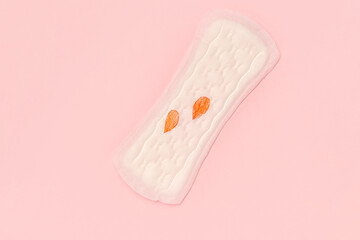 Women's daily hygiene pad on a pink background and painted droplets symbolizing blood