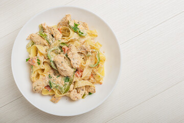 Cajun chicken Fettuccine pasta in a creamy sauce on white plate. Top view.