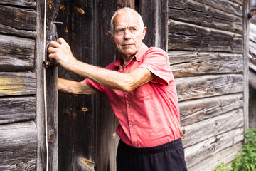 senior pensioner in red polo posing near the house in the village