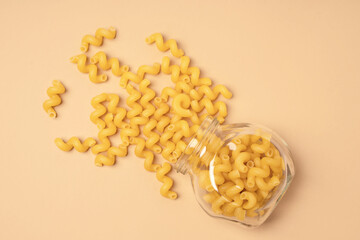Pasta in the form of a curly spiral in a glass jar on a beige background