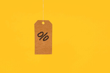 Tags with drawn percentages hang on strings on a yellow background, concept of discounts and sales