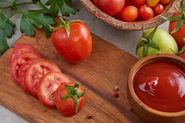 tomato sauce with garlic and  vibrant green leaves of the italian parsley plant. tomato ketchup sauce in a bowl with spices, herbs and cherry tomatoes. top view.