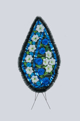 Wreath with artificial flowers for tombstone on gray background