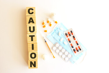 The word CAUTION is made of wooden cubes on a white background. Medical concept.