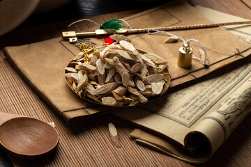 Astragalus membranaceus，Ancient Chinese medicine books and herbs on the table.English...