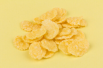 Pile of yellow cornflakes on yellow  background