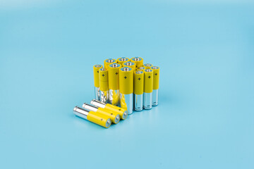 Photo of gray-yellow alkaline AA batteries on blue background. Recycling of rechargeable NiMH...