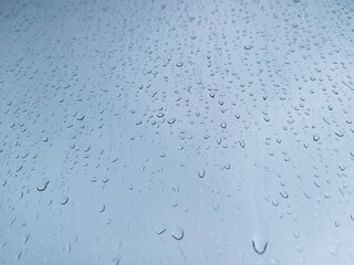 Raindrops on a window pane close-up. Abstract blue background.