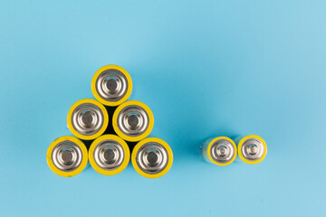 Photo of gray-yellow alkaline AA batteries on blue background. Recycling of rechargeable NiMH...