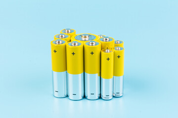 Photo of gray-yellow alkaline AA batteries on blue background. Recycling of rechargeable NiMH...