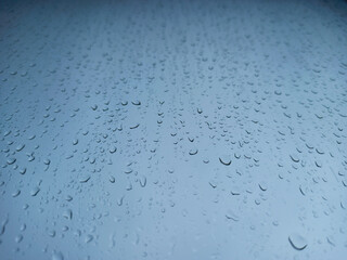 Raindrops on a window pane close-up. Abstract blue background.