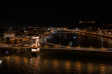 Fototapeta na wymiar Aerial view of illuminated Budapest Chain Bridge at night with dark sky and reflection in Danube river. Panoramic view of hungarian famous bridge. Budapest, Hungary at night.